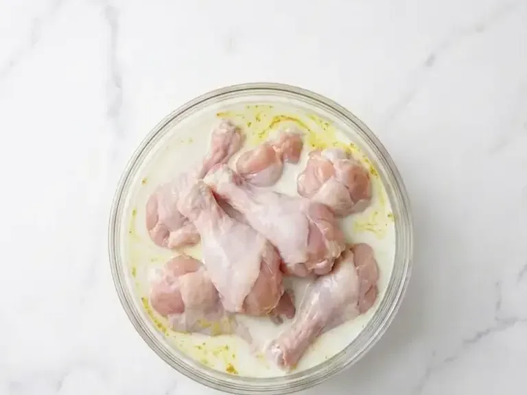 Chicken drumettes marinating in milk and curry powder for yangnyeom chicken recipe