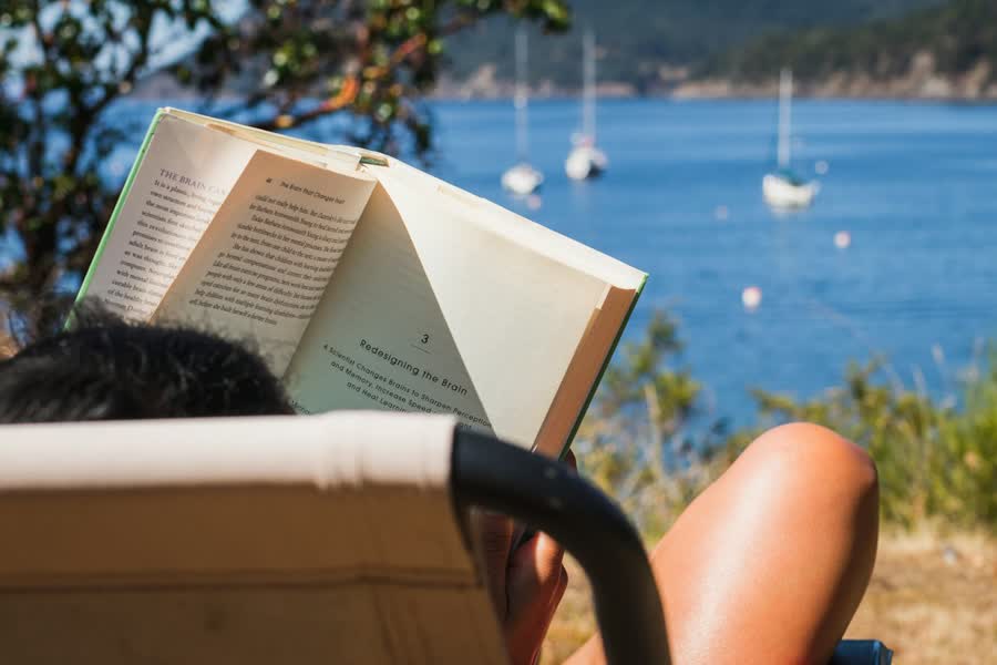 Digital detox weekend routine: reading a paper book in a deck chair by the sea