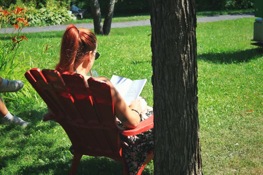 Digital detox weekend routine: reading a paper book in a red garden chair