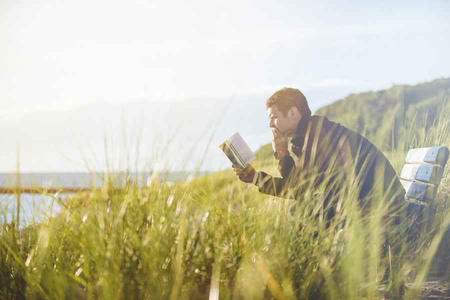 Digital detox weekend routine: a man reading in tall grass with no phone in sight