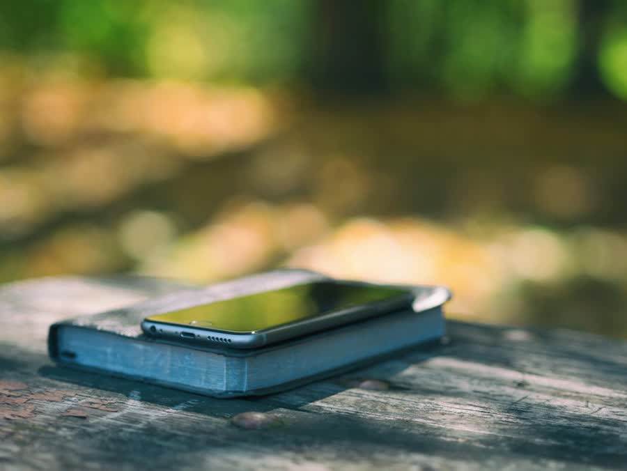 Digital detox weekend routine: a phone left face-down on a closed book outdoors