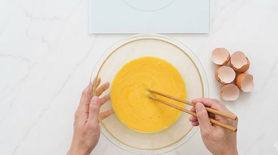 thirteen eggs beaten in a glass bowl for the thick kimbap recipe egg sheet