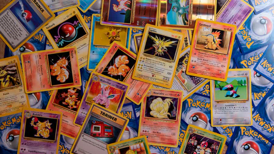 Raw vintage Pokémon cards on a table before a PSA vs CGC vs BGS decision